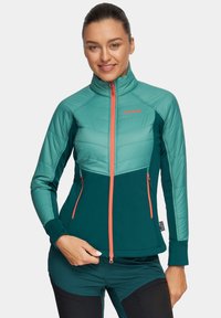 Wodoodporna kurtka izolacyjna w kolorze turkusowym i ciemnozielonym z wysokim kołnierzem, zapinanymi na zamek kieszeniami i kontrastującym pomarańczowym zamkiem. Dopasowany krój z fakturowanymi panelami.