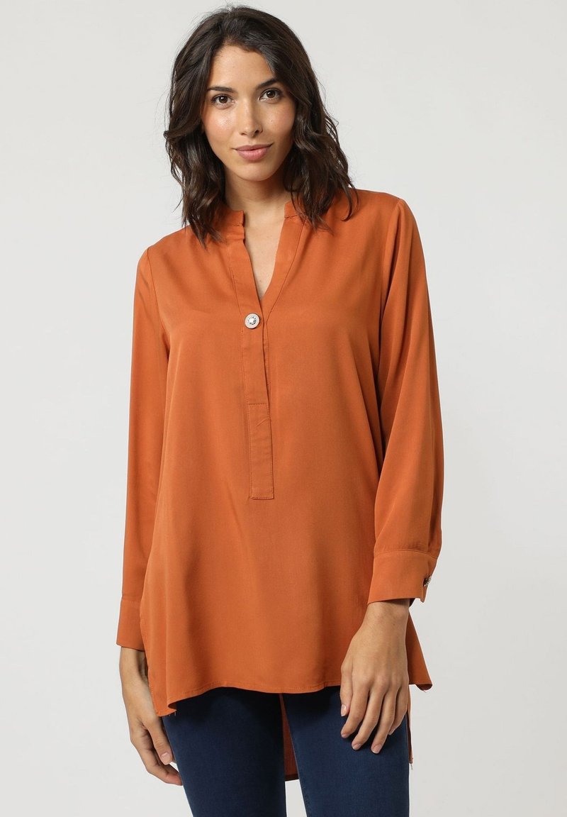 Camisa de manga larga color óxido con cuello con muesca y tapeta de botones en la parte frontal. Tejido suave y liso con un corte relajado y aberturas laterales.