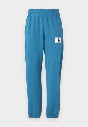 Teal katoenen joggerbroeken met elastische tailleband en boorden, met zijzakken en een wit label met het "CK" -logo.