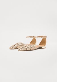 Ballerines en matériau tissé champagne avec des brides de cheville ; orteils pointus et accent de petit talon métallique ; tige texturée avec un motif complexe.