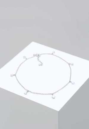 Sølv kædearmbånd med stjerne charms, der har et fint linksdesign og justerbar lås, placeret mod en neutral baggrund.