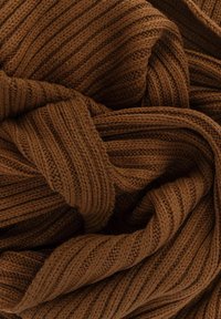 Ciemnobrązowa dzianina o prążkowanej strukturze, z nakładającymi się fałdami i różną grubością włókna.