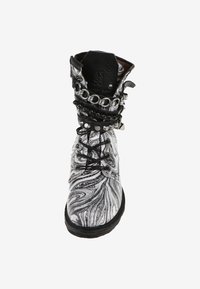 Bota de cuero veteada en blanco y negro con cordones en la parte delantera, punta afilada y cadenas y tachuelas decorativas alrededor del puño.