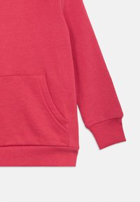 Κόκκινο φούτερ με μπροστινή τσέπη, ριμπ μανσέτες και υφασμάτινο σχέδιο. Το ύφασμα είναι μαλακό και ελαστικό.