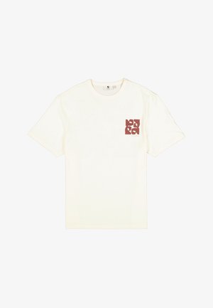 Camiseta color crema con cuello redondo, mangas cortas y un diseño gráfico burdeos en el pecho izquierdo. Hecha de tela de algodón suave.