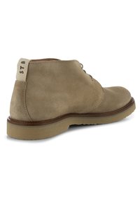 Stivale alla caviglia in suede beige con punta rotonda, chiusura a lacci e suola in gomma leggera. Presenta una linguetta sul tallone in tessuto con la scritta "STB".