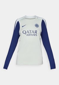 Maillot de football à manches longues en gris clair avec des manches bleu marine. Il possède un col rond, un logo Nike et un marquage Qatar Airways sur le devant.