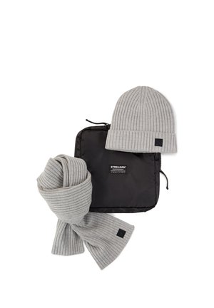 Graue gerippte Strickmütze und passender Schal neben einer schwarzen Tasche mit Reißverschluss und weißem Strellson-Logoetikett.