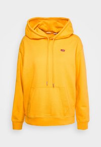 Sudadera amarilla de tejido suave, con un bolsillo frontal, capucha con cordón y pequeño logo rojo de Levi's en el pecho. Textura lisa.