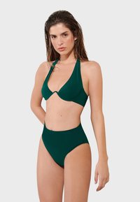 Zielony zestaw bikini składający się z topu na halterze o głębokim dekolcie i wysokich majtkach, wykonany z gładkiego materiału bez widocznych wzorów.