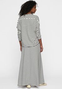 Top de manga larga a rayas en blanco y negro con un corte holgado, combinado con una falda larga a juego, ambos hechos de una tela suave y ligera.