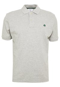 Harmaa puuvillapaita, jossa on klassinen kaulus, kaksinappinen nappilista ja pieni vihreä puu-logo vasemmassa rinnassa.