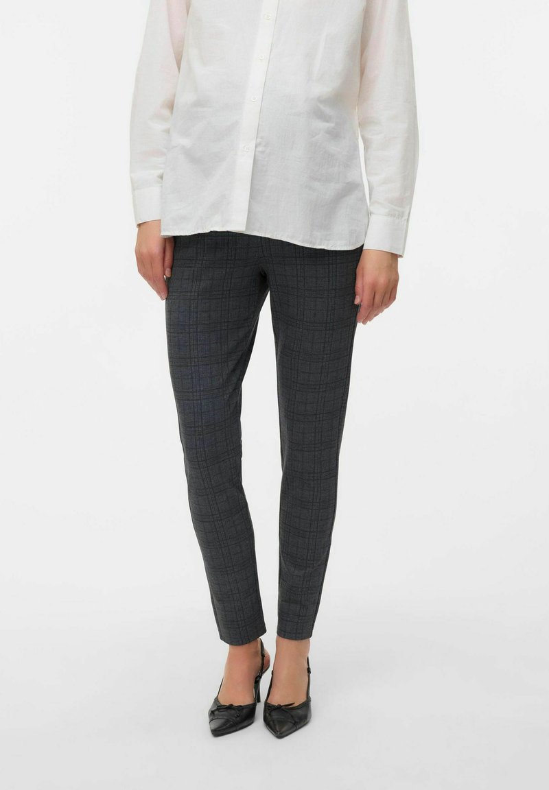 Pantalons à carreaux gris avec une coupe slim, fabriqués en tissu doux, associés à une chemise blanche à boutons et des escarpins pointus noirs.