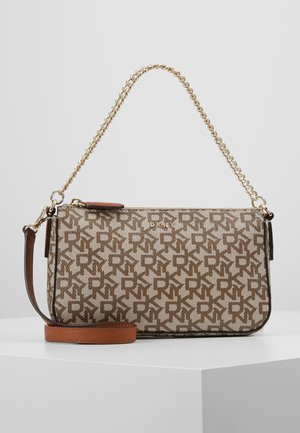 Hnědá DKNY monogramová kabelka s držadlem ze zlatého řetízku a odnímatelným koženým ramenním popruhem na bílém pozadí.
