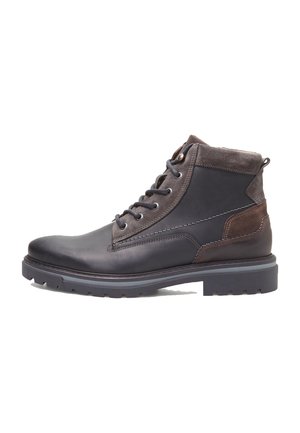 Botas de tobillo de piel negra con acentos de ante marrón, cordones redondos y una suela de goma texturizada. Presentan un collar acolchado y detalles acolchados.