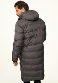 Langer grauer Steppmantel mit Kapuze, einem gesteppte Design und Seitentaschen. Das Material wirkt glatt und isoliert für Wärme.