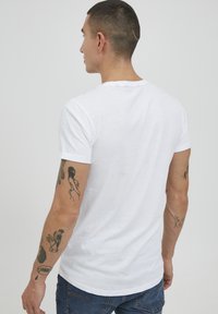 Hvid bomulds t-shirt med korte ærmer. Rund halsudskæring og en afslappet pasform. Har en glat tekstur og syninger ved kanten og ærmerne.