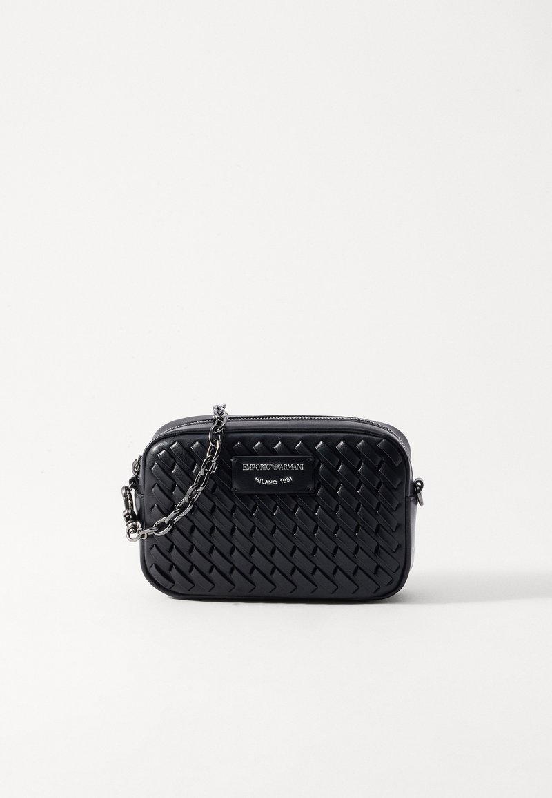 Bolsa crossbody de couro tecida preta com alça de corrente prateada e placa com logotipo. Apresenta um formato retangular e fecho em zip. Design compacto.