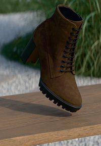 Braune Wildleder-Stiefelette mit einem stabilen Absatz und Schnürung an der Vorderseite. Verfügt über ein strukturiertes Obermaterial und eine robuste Gummisohle.