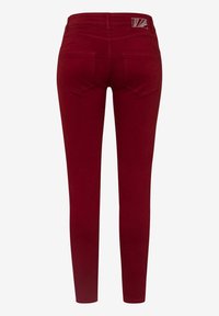 Vaqueros skinny burdeos con una textura suave, que presentan una cinturilla alta, dos bolsillos traseros y un pequeño parche con el logotipo cerca de la cinturilla.