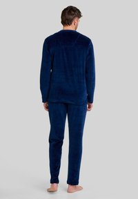 Conjunto de pijama de forro polar azul marino, que incluye una camiseta de manga larga y pantalones a juego con una textura suave, diseñado para la comodidad y el calor.