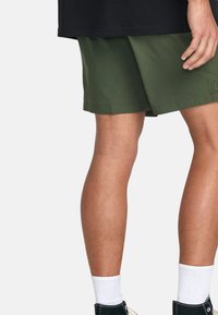 Pantaloni corti verdi realizzati in un materiale leggero, caratterizzati da una vestibilità comoda, linee pulite e una vita con un sottile dettaglio del logo.