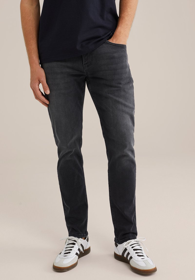 Tamne traperice u tamno sivoj boji, uskog kroja. Imaju klasičan dizajn s pet džepova, suptilno izbleđivanje i mekani materijal. Nosi se s bijelim tenisicama.