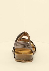 Hnědá kožená sandála s otevřenou zadní částí, třemi nastavitelnými popruhy, texturovanou stélkou a plochou gumovou podrážkou. Design je jednoduchý a funkční.