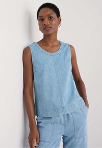 Jasnoniebieska, bezrękawnikowa bluzka dżinsowa z okrąg�łym dekoltem, posiadająca widoczne szwy i luźny krój, w zestawie z pasującymi dżinsowymi spodniami.