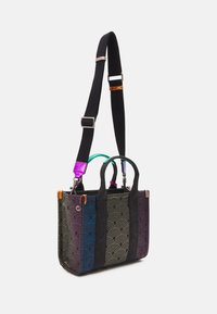 Czarna torba tote z tkaniny z multikolorowym wzorem fal, regulowanym paskiem, dwoma górnymi uchwytami i metalowymi akcentami.