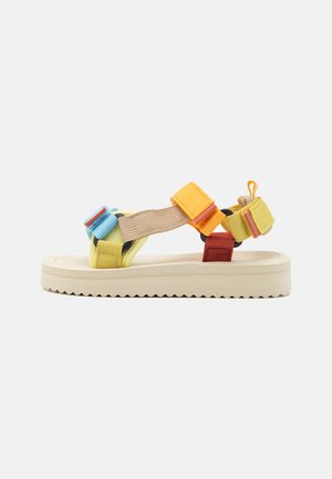 Multicolored sandal with yellow, blue, and red straps made of textile. Thick cream sole with a zigzag tread pattern.
