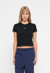 Černé zkrácené tričko z elastického materiálu s kulatým výstřihem a krátkými rukávy. Na hrudi má malé bílé logo Nike.
