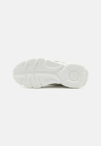 Semelle de chaussure avec de profonds canaux pour l'adhérence, fabriquée en caoutchouc blanc, présentant une forme arrondie et une légère courbure au niveau du talon.