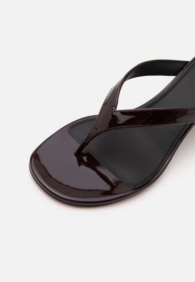 Close-up of a shiny dark brown thong sandal with a square toe and black cushioned footbed on a light background.