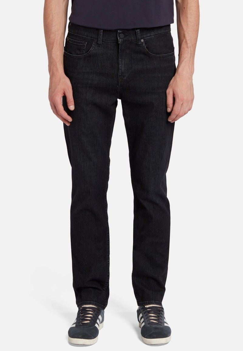 Jeans in denim nero con una vestibilità dritta, design a cinque tasche, chiusura a bottoni, leggera scoloritura e abbinati a sneakers grigie.