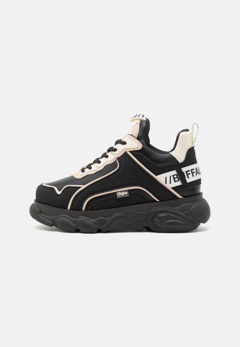 Schwarze und cremefarbene Sneaker mit einer dicken Sohle, aus Textil- und Synthetikmaterialien, abgerundeten Akzenten und einem markenbezogenen Detail an der Ferse.