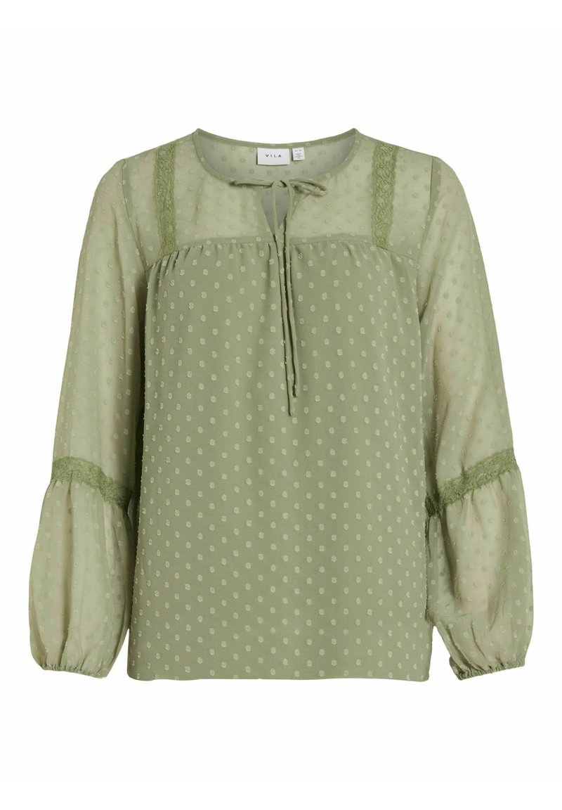Blusa verde a pois con un taglio morbido, caratterizzata da un collo rotondo, un dettaglio con nodo e maniche a sbuffo trasparenti con accenti in pizzo sulle spalle.
