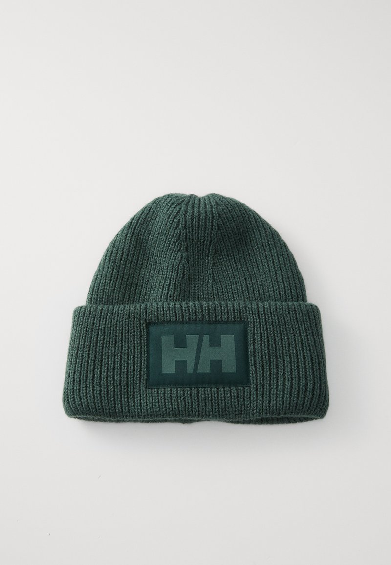 Grønn strikket lue med brettet opp kant, utstyrt med et rektangulært logopatch i mørkere grønn som viser initialene "HH." Teksturert ribbestrikket mønster.