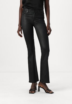 Black flared jeans made of smooth denim, featuring a high waistband, subtle stitching, and a fitted silhouette, paired with black heeled sandals.