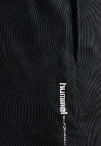 Svarta atletiska shorts med en subtil randig textur, med vit "hummel"-logotyp på sidan samt "PERFORMANCE" nedanför.