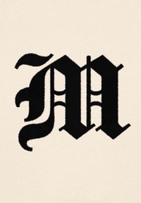 Lettera "M" nera ricamata su uno sfondo beige chiaro, caratterizzata da dettagli ornati e curvi e punte affilate, che creano un forte contrasto visivo.