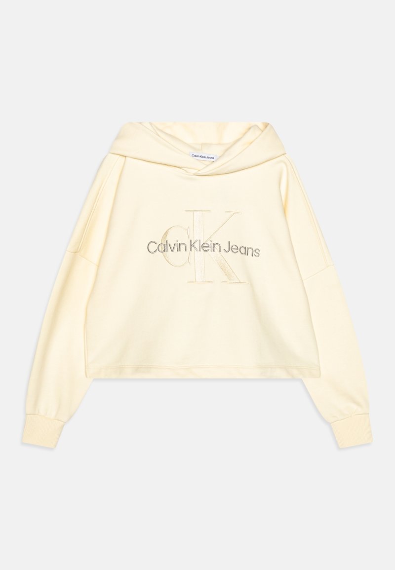 Sweat à capuche court de couleur crème avec manches longues et poignets côtelés, arborant une broderie "Calvin Klein Jeans" et un grand logo "CK" sur le devant.