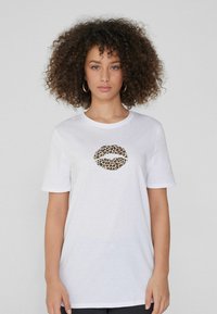 Camiseta de algodón blanca con un gráfico de labios con estampado de leopardo en el centro. Mangas cortas, escote redondo, corte holgado, textura suave.