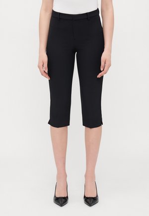 Pantalons cropped noirs avec un design ajusté, dotés d'une texture lisse, de poches avant et d'un ourlet qui s'élargit légèrement.