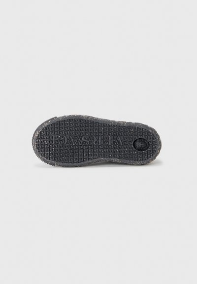 Suela de zapato de goma negra con un patrón texturizado, nombre de la marca y pequeñas motas claras. Bordes ascendentes y forma de punta redondeada.