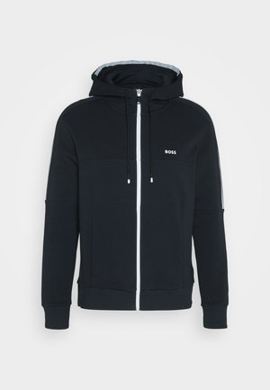 Black zip-up hoodie made from soft fabric, featuring a front zipper, side pockets, and a logo on the chest. Includes adjustable drawstrings.