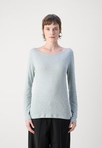 Šviesiai mėlynas ilgomis rankovėmis viršus, pagamintas iš minkštos, tekstūruotos medžiagos su plačia iškirpte. Derinamas su tamsiais plačiais kelnių.