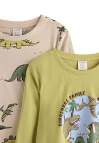 Zwei Baumwoll-T-Shirts: eines in Beige mit grünen Dinosaurier- und Palmenmotiven, eines in Hellgrün mit einem runden Dinosaurier-Familienmotiv.