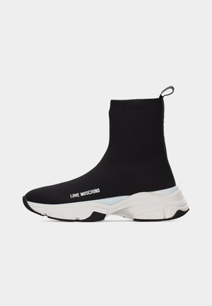 Fekete zoknistílusú sportcipő fehér vastag talppal és "LOVE MOSCHINO" felirattal az oldalon, hátul húzófüllel, fehér háttéren izolálva.