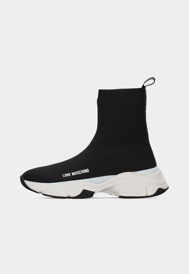 Μαύρο αθλητικό παπούτσι σε στυλ κάλτσας με άσπρη χοντρή σόλα και το κείμενο «LOVE MOSCHINO» στο πλάι, με θηλιά στο πίσω μέρος, απομονωμένο σε λευκό φόντο.